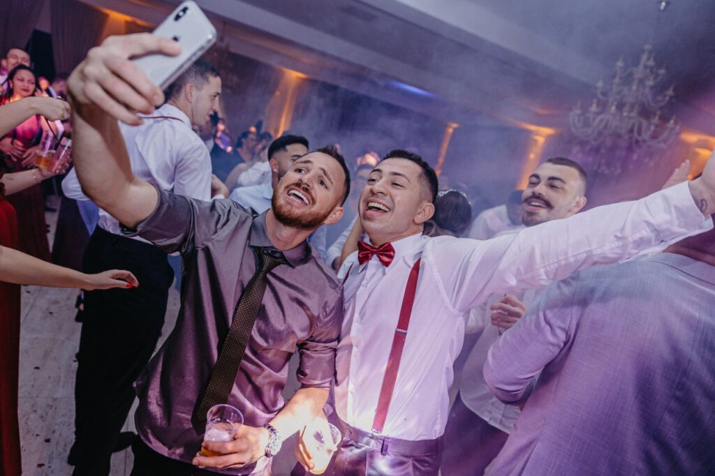 Group of friends enjoying a lively party, capturing the moment with a smartphone selfie